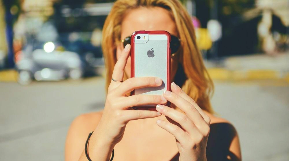 Featured | Girl Holding iPhone | iPhone Hacks That Will Make Your Life Easier